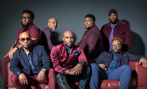 Die Band Naturally7 auf einem Sofa sitzend und dahinter stehend.